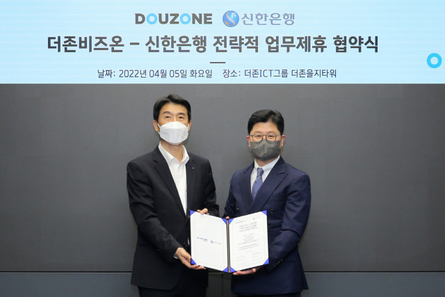 왼쪽부터 최익성 신한은행 부행장과 더존비즈온 지용구 솔루션사업부문 대표가 업무 협약서를 교환하고 있다.