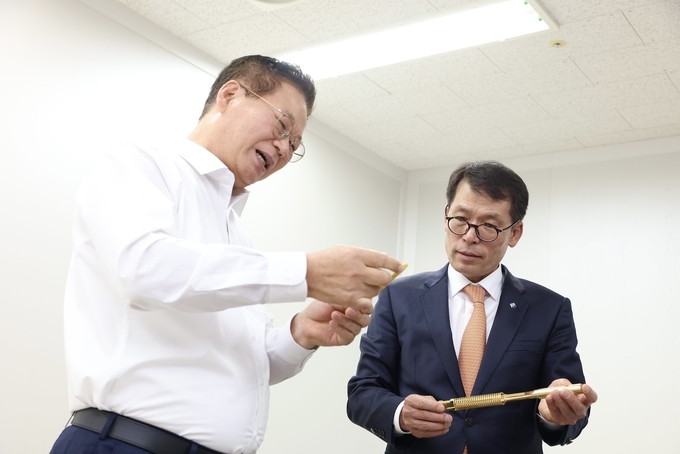  9일 김성태 IBK기업은행장(오른쪽)이 성남산업단지에 소재한 하이콘을 방문해 황동원 대표(왼쪽)에게 반도체 테스트 소켓에 대한 설명을 듣고 있는 모습.