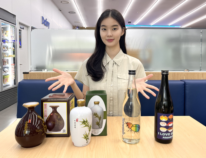 GS25에서 모델이 아이 러브 스시 사케를 바라보고 포즈를 취하고 있다.